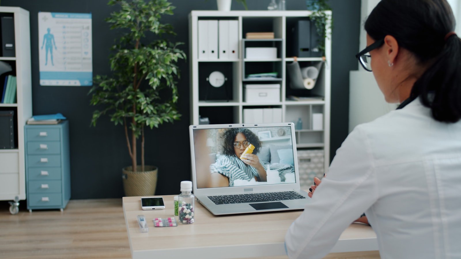 Médica conduzindo teleconsulta com paciente por videochamada no laptop